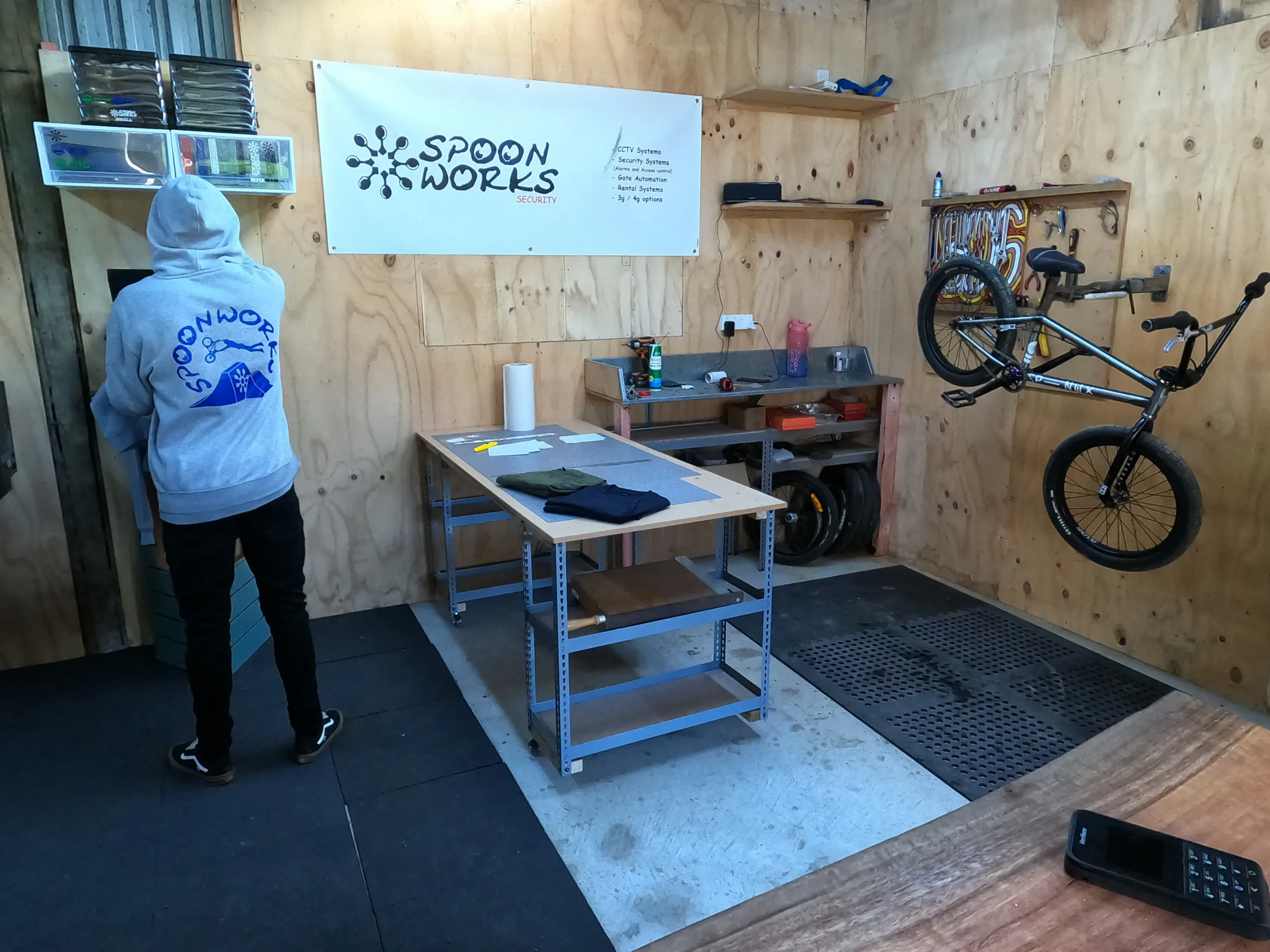 Inside the Spoonworks workshop - a team hoodie, a BMX bike on the wall and the security bench